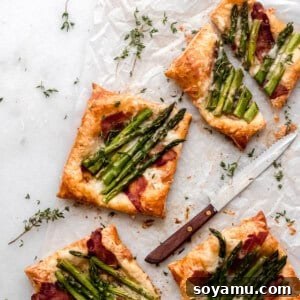 Four puff pastry asparagus tarts on a white surface.