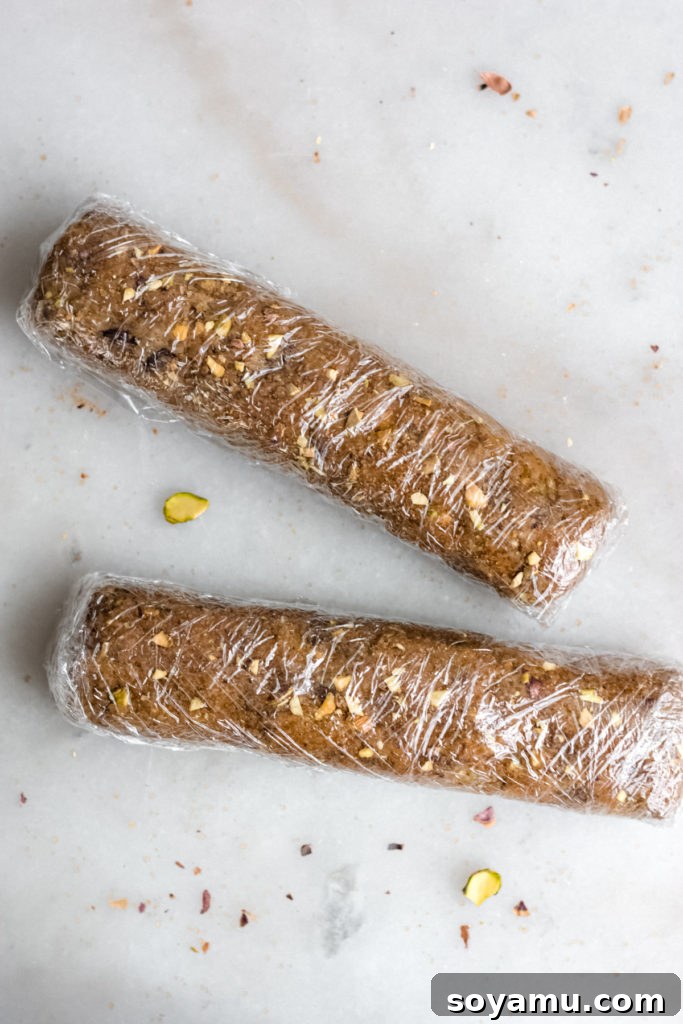 Cookie dough logs wrapped tightly in plastic wrap, ready for chilling.