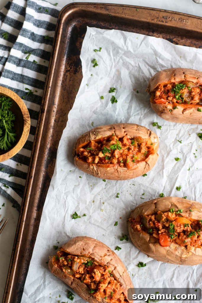 Nourishing Homemade Sloppy Joes 2 Four homemade sloppy joes over sweet potatoes on a tray, garnished with fresh herbs.