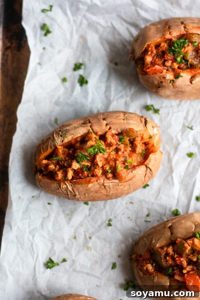 Nourishing Homemade Sloppy Joes 6 Top-down view of three sloppy joes stuffed sweet potatoes, garnished with cheese and herbs.
