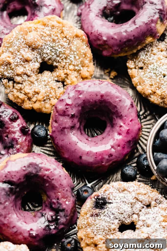 A close-up of a mix of streusel-topped and blueberry glazed donuts arranged on a tray, ready for serving.