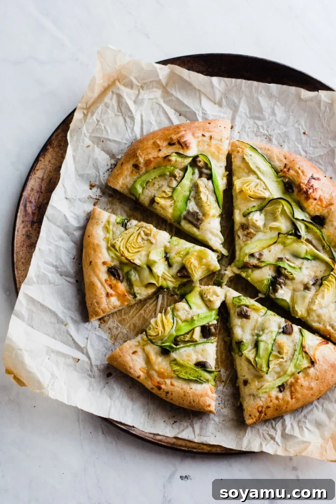 Green Goddess Pizza - Tastes like Spinach Artichoke Dip Green goddess pizza sliced on a board, showcasing vibrant green vegetables and melted cheese.