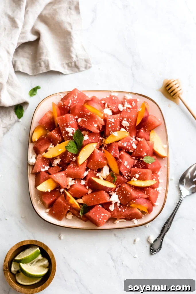 Watermelon nectarine salad with feta and honey lime dressing, beautifully arranged on a plate.