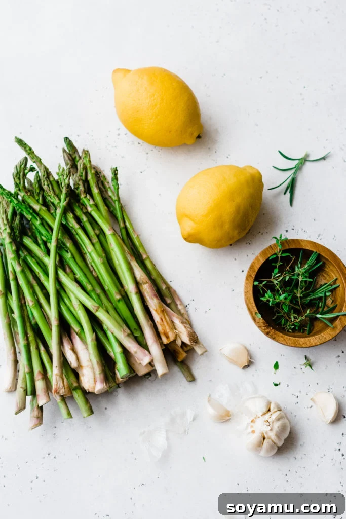 Essential fresh ingredients for Lemon Garlic Chicken with Asparagus. Fresh asparagus, garlic cloves, and bright lemons on a white cutting board.