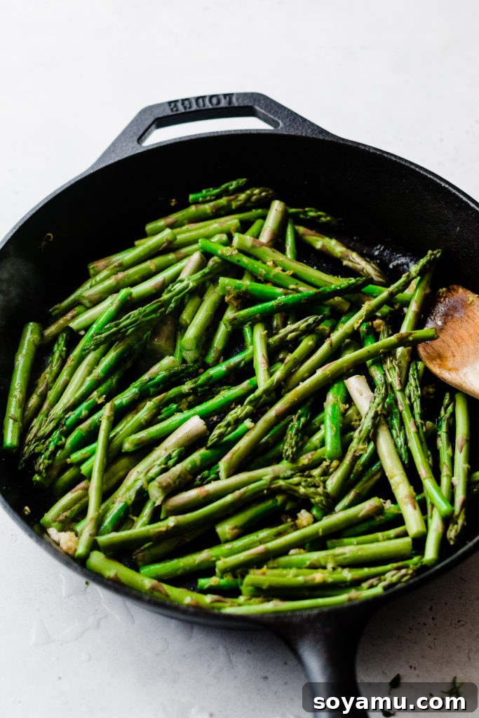 Sautéing asparagus to crisp-tender perfection. Asparagus cooking in a cast iron skillet with lemon and garlic.