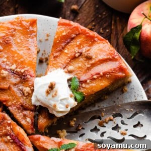 A close-up on slices of the peach upside down cake on a plate, topped with whipped cream.
