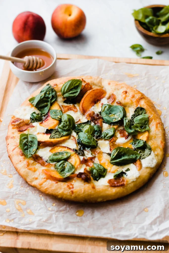 Close-up of a sliced peach pizza on a wooden cutting board, garnished with fresh basil.