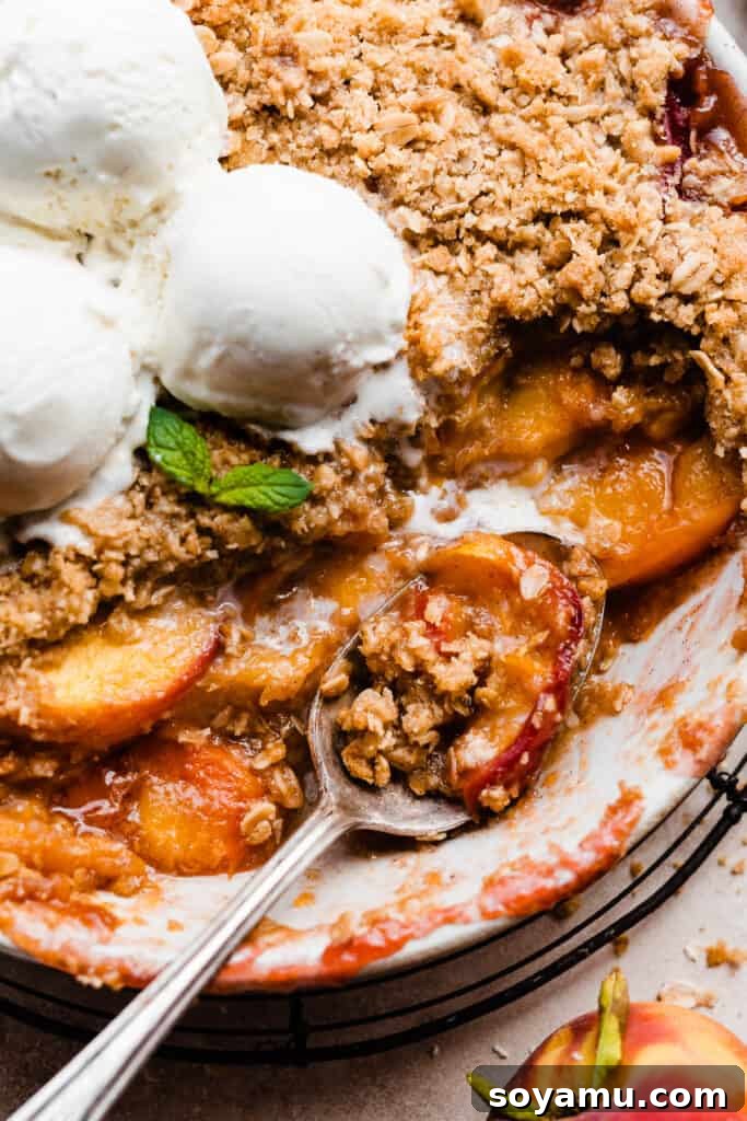 Heavenly Brown Butter Peach Crisp 11 A close-up of a spoon being used to scoop a serving of the warm, golden brown peach crisp from the baking dish.