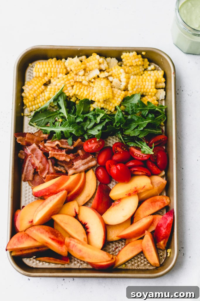 Individual ingredients for the peach nectarine salad, including corn, nectarine slices, cherry tomatoes, bacon, and arugula, arranged on a tray.