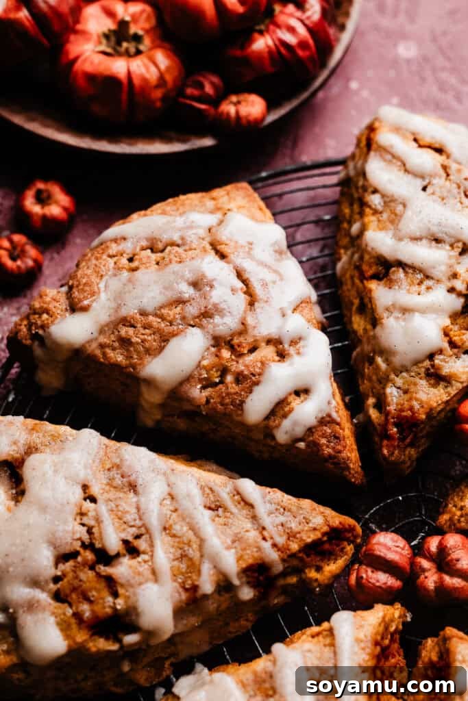 A close-up of a pumpkin scone drizzled with maple glaze, on a vintage wire rack. Keywords: Pumpkin Scones, Maple Glaze, Fall Baking, Scone Recipe.