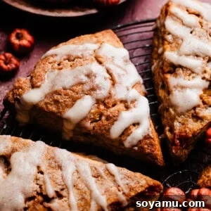 A close-up on a glazed pumpkin scone, highlighting its texture and delicious glaze. Keywords: Pumpkin Scones Recipe, Maple Glaze Scones, Fall Scones.
