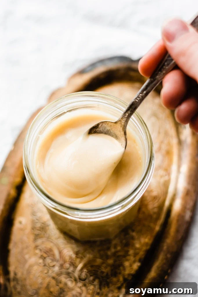 Spoonful of maple glaze, being spooned out of a glass jar and shown to camera. Keywords: Maple Glaze, Scone Glaze, Sweet Topping.