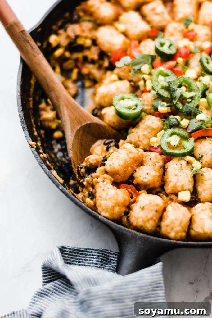 Healthier Tater Tot Casserole - A MidWestern Comfort Food Classic Close-up view of the golden, crispy tater tots topping a creamy, savory casserole filling in a cast iron skillet.