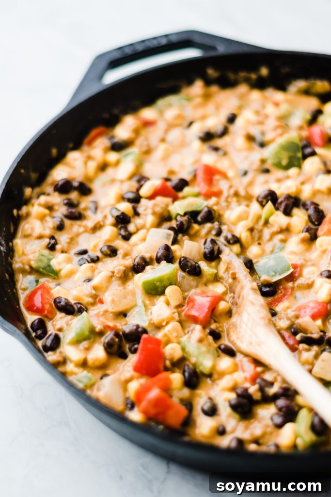 Homemade Tater Tot Hot Dish Filling with Fresh Vegetables A rich, savory filling for tater tot hot dish simmering in a cast iron skillet, full of ground meat, vegetables, and creamy sauce.