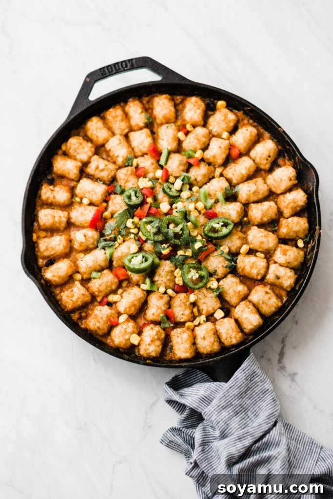 Completed Healthier Tater Tot Hot Dish A glorious, baked Tater Tot Hot Dish in a cast iron skillet, garnished with fresh herbs, ready to be enjoyed as a hearty family meal.