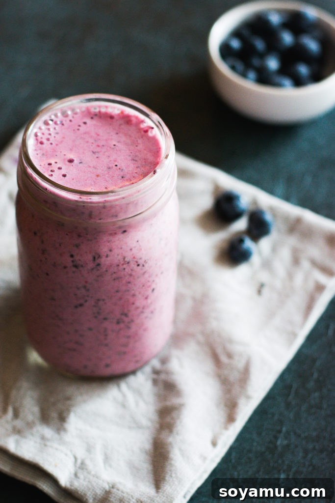 Effortless Vitality: 4 Wholesome Smoothie Creations 5 A vibrant red berry smoothie in a clear glass, garnished with fresh mint, sitting on a wooden surface.