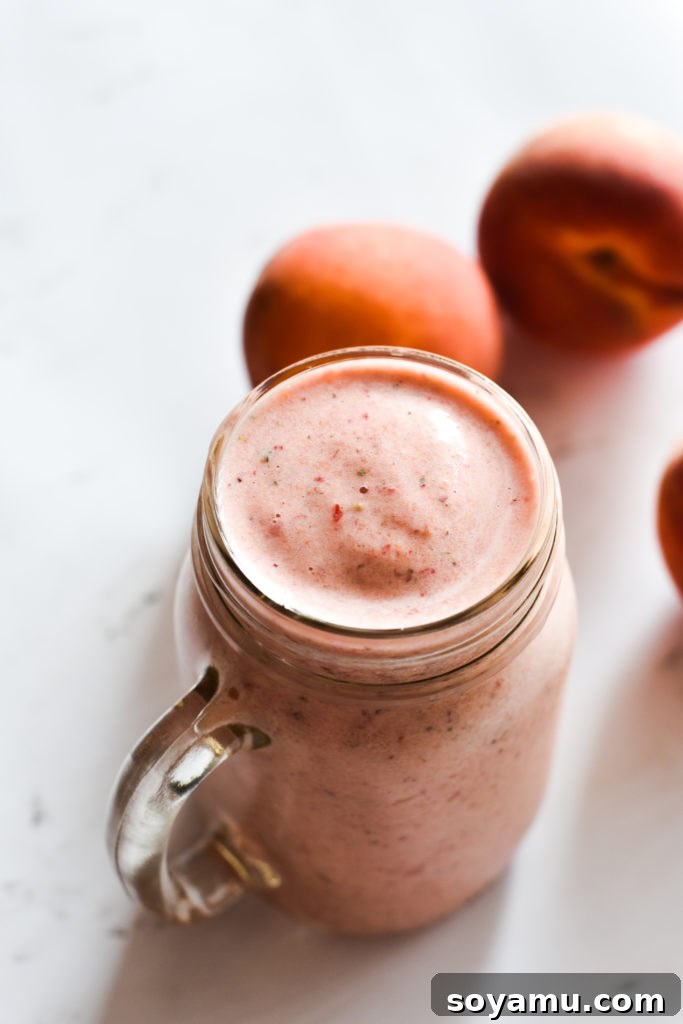Effortless Vitality: 4 Wholesome Smoothie Creations 7 A close-up shot of a peach and strawberry smoothie, showing its smooth texture and vibrant color.