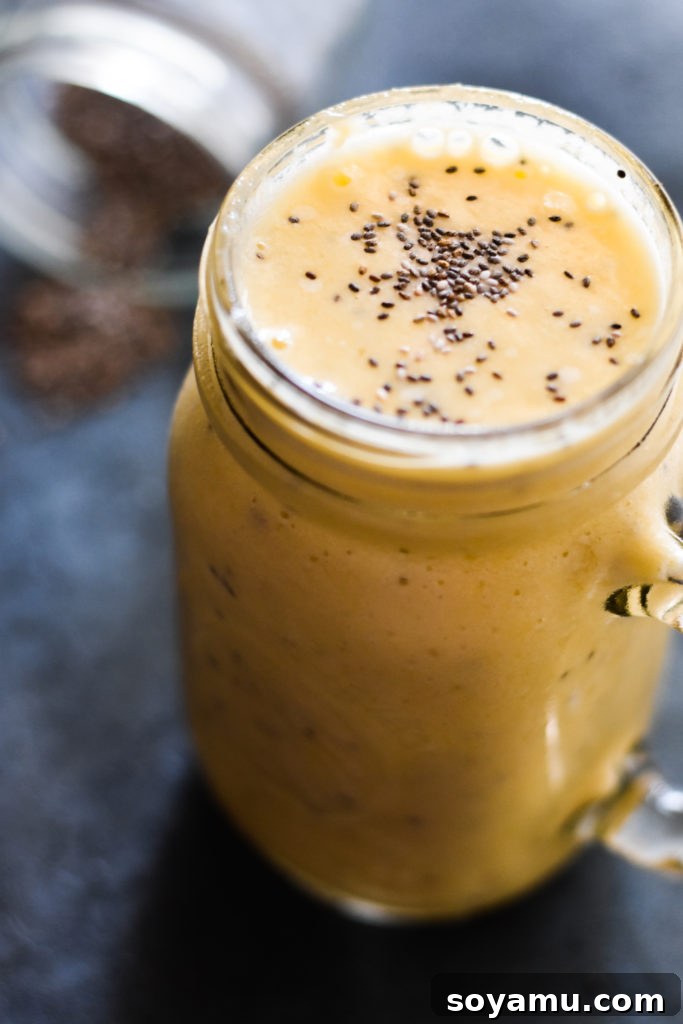 Effortless Vitality: 4 Wholesome Smoothie Creations 8 A sunny yellow mango and pineapple smoothie in a glass, garnished with a pineapple wedge and mint.