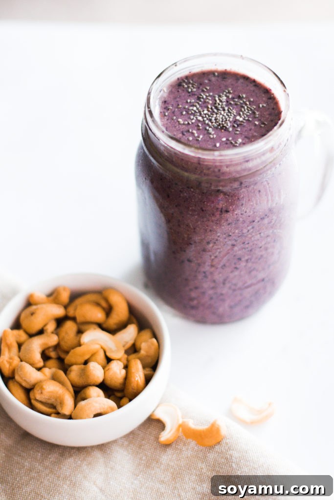 Effortless Vitality: 4 Wholesome Smoothie Creations 9 A vibrant purple blueberry smoothie in a glass, topped with fresh blueberries and a sprinkle of nuts.