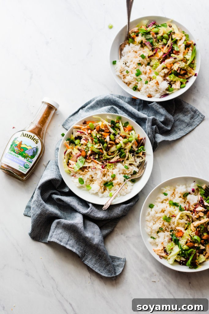 Bottle of Annie's Organic Asian Sesame Dressing beside a bowl of prepared chicken and mixed vegetables.