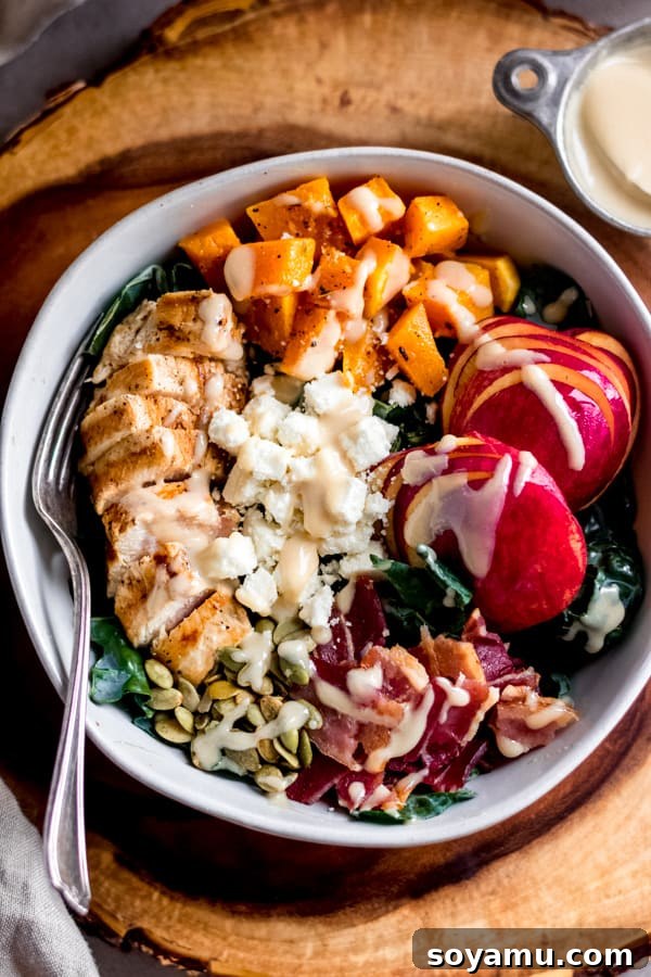 Fall Harvest Salad with Maple Tahini Dressing A vibrant fall harvest salad topped with roasted butternut squash, chicken, feta, and a rich maple tahini dressing, presented in a large bowl.