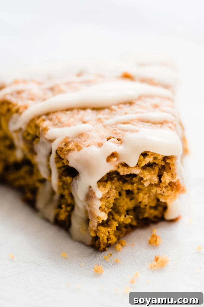 Pumpkin Scones with Bourbon Maple Vanilla Glaze Fluffy pumpkin scones drizzled with a rich bourbon maple vanilla glaze, resting on a white plate with autumn decorations.
