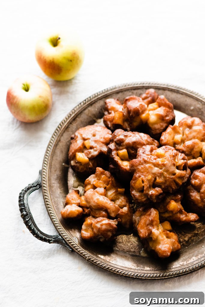 Apple Fritters with Buttery Maple Glaze Warm homemade apple fritters generously coated in a buttery maple glaze, stacked on a plate and ready to be enjoyed as a comforting fall treat.