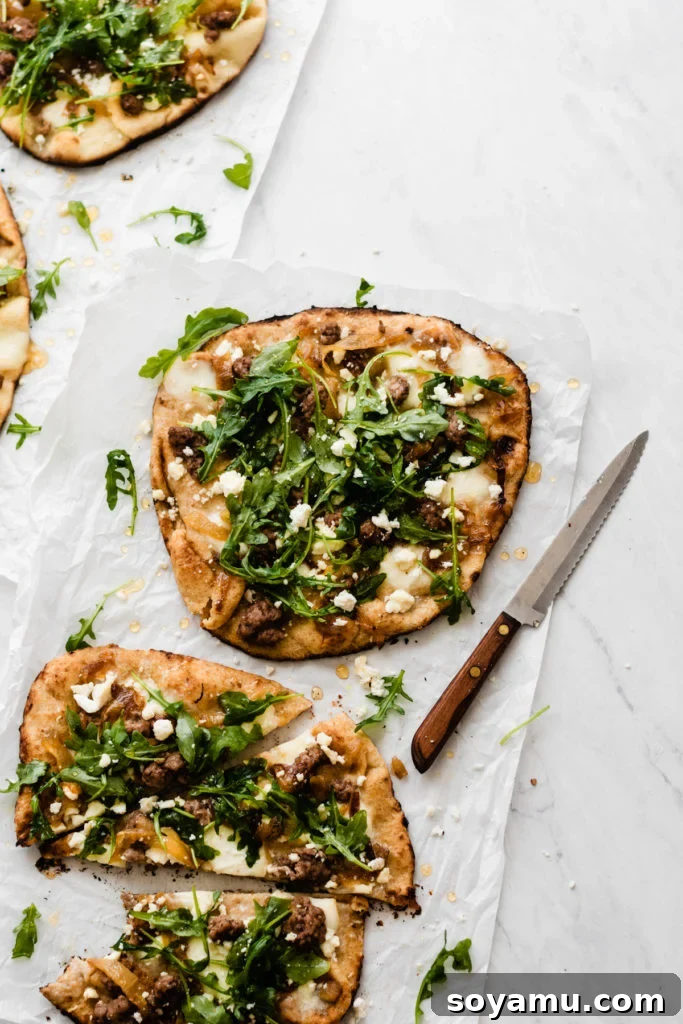 An array of delicious grilled lamb pizzas with arugula and honey laid out on a large baking sheet, perfect for a gathering