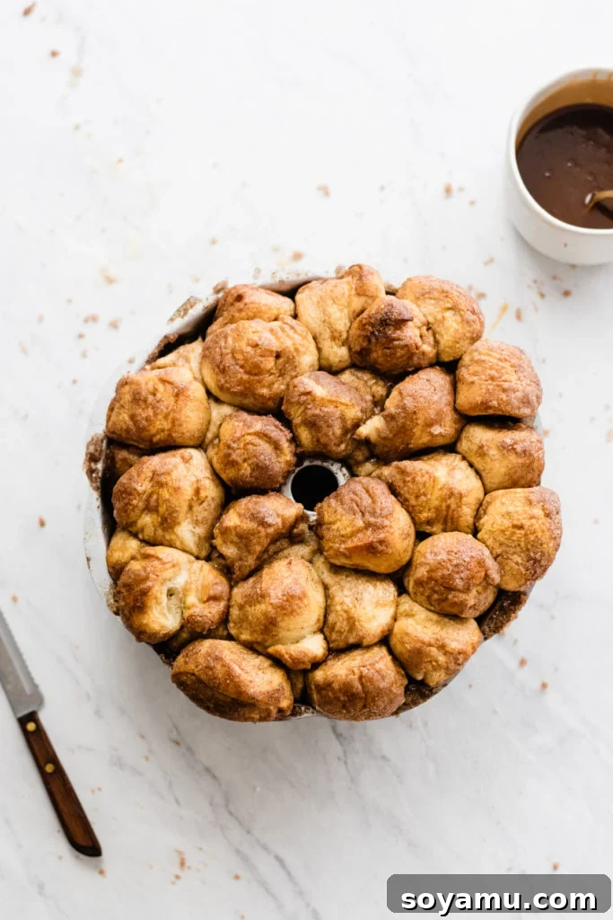 Freshly baked Monkey Bread, golden and puffy, visibly rising out of the bundt pan, with a hint of bubbling caramel.