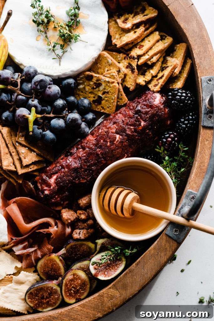 Autumn Bounty Board 4 A bird's eye view of a detailed corner of the fall charcuterie board, showcasing a drizzle of honey over goat cheese, fresh figs, assorted crackers, and dark chocolate pieces.