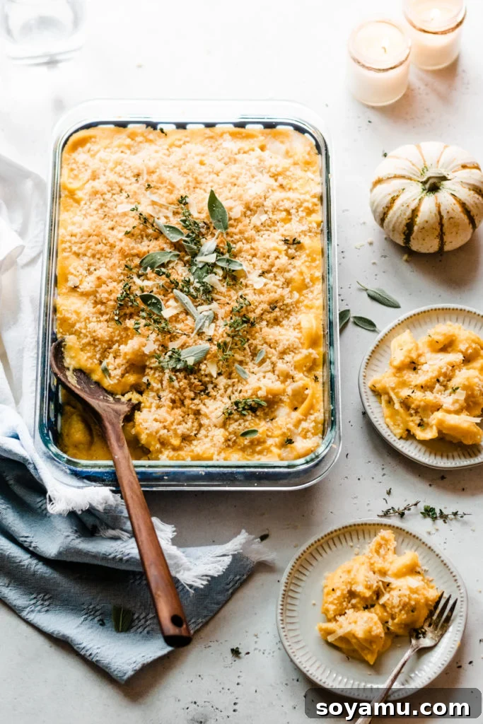 Baked Butternut Squash Mac and Cheese - Incredibly creamy, flavorful, & easy to make! Made with creamy butternut squash sauce, cheddar, parmesan, & smoked gouda cheese, fresh thyme + sage, and a crispy, buttery bread crumb topping. This side will be the star of your Thanksgiving meal! #macandcheese #easyrecipe #vegetarianrecipes #dinnerrecipes #sidedishrecipes #butternutsquashrecipes #thanksgivingrecipes #bluebowlrecipes | bluebowlrecipes.com A beautifully baked pan of butternut squash mac and cheese, with individual servings plated next to it, ready for a meal.