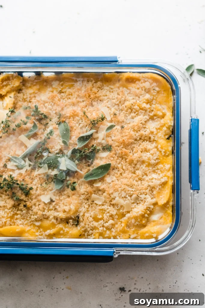 Baked Butternut Squash Mac and Cheese - Incredibly creamy, flavorful, & easy to make! Made with creamy butternut squash sauce, cheddar, parmesan, & smoked gouda cheese, fresh thyme + sage, and a crispy, buttery bread crumb topping. This side will be the star of your Thanksgiving meal! #macandcheese #easyrecipe #vegetarianrecipes #dinnerrecipes #sidedishrecipes #butternutsquashrecipes #thanksgivingrecipes #bluebowlrecipes | bluebowlrecipes.com A full baking pan of the golden-brown, bubbly baked butternut squash mac and cheese, fresh from the oven.