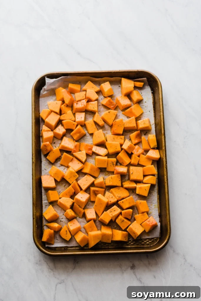 Seasoning Butternut Squash for Roasting Butternut squash tossed with olive oil, sage, thyme, salt, pepper, and optional brown sugar on a baking sheet, ready for roasting.