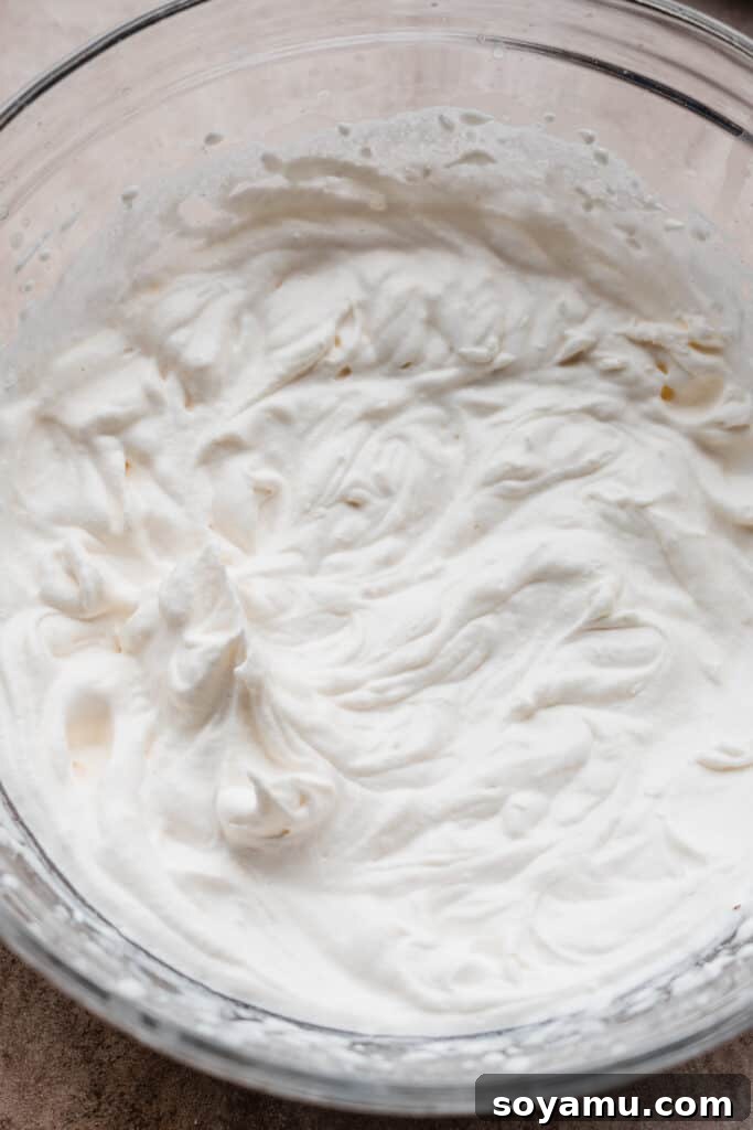 Freshly made whipped cream topping A medium bowl filled with light, fluffy, and perfectly peaked homemade whipped cream, ready to be used as a topping.