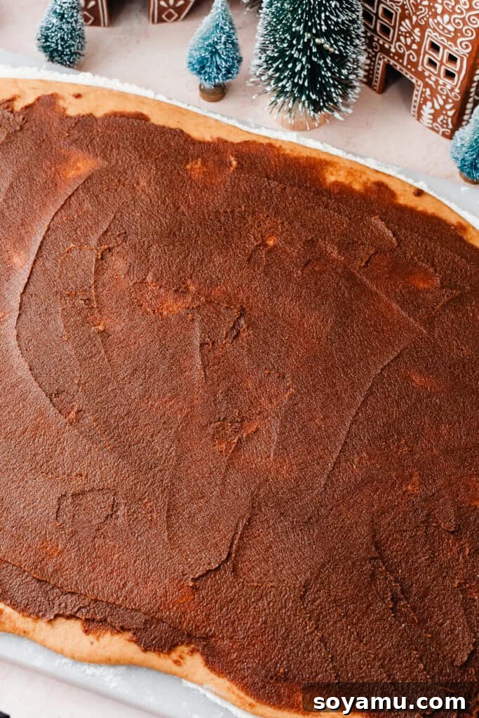 The spiced gingerbread cinnamon filling spread evenly across the rectangular dough, ready for the next step.
