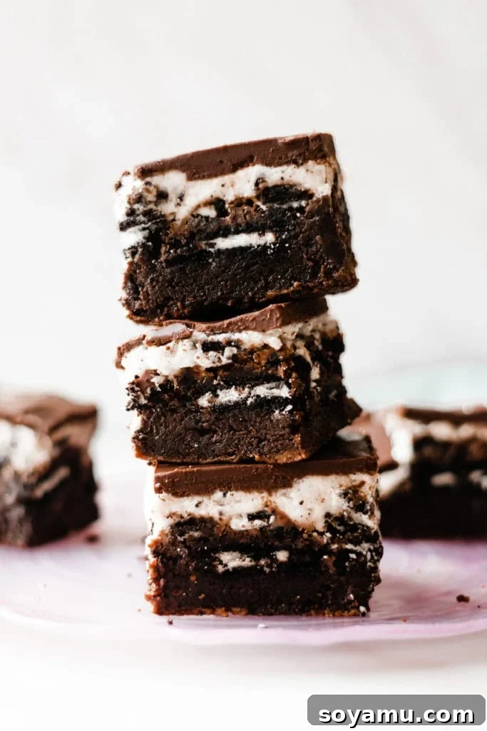 Ultimate Cookies & Cream Bars - The holiday treat to end all holiday treats! Made with a layer of thick, fudgy brownies that have a layer of oreos in the middle, & topped with sweetened condensed milk + crushed oreos. Next up, a layer of oreo frosting and a layer of chocolate to top it all off! This is the stuff of chocolate dreams! #dessertrecipes #christmascookies #brownies #oreo #christmasbaking #christmasrecipes #cookierecipes #frosting #chocolate #bluebowlrecipes | bluebowlrecipes.com Ultimate Cookies & Cream Bars, a layered dessert featuring fudgy brownies, whole Oreos, sweetened condensed milk, crushed Oreos, creamy Oreo frosting, and a chocolate ganache topping. Perfect for holiday dessert recipes and Christmas baking. #dessertrecipes #christmascookies #brownies #oreo #christmasbaking #christmasrecipes #cookierecipes #frosting #chocolate #bluebowlrecipes