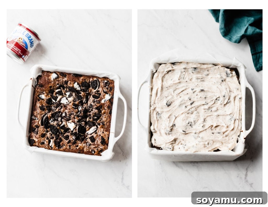 Ultimate Cookies & Cream Bars - The holiday treat to end all holiday treats! Made with a layer of thick, fudgy brownies that have a layer of oreos in the middle, & topped with sweetened condensed milk + crushed oreos. Next up, a layer of oreo frosting and a layer of chocolate to top it all off! This is the stuff of chocolate dreams! #dessertrecipes #christmascookies #brownies #oreo #christmasbaking #christmasrecipes #cookierecipes #frosting #chocolate #bluebowlrecipes | bluebowlrecipes.com Creamy Oreo frosting being perfectly spread over cooled brownie bars, revealing delightful crushed Oreos and enhanced with sweetened condensed milk. This image captures a key layer in crafting Ultimate Cookies & Cream Bars, a truly decadent holiday cookie. #oreofrosting #desserttopping #creamyfrosting