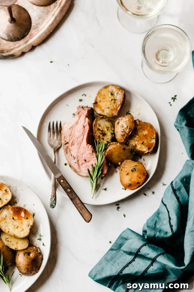 A close-up of the beautifully roasted lamb and potatoes, showcasing their golden crust and tender texture. Lamb Roast and Herbed Garlic Butter Potatoes close up - A perfectly roasted lamb leg alongside golden, crispy potatoes infused with garlic and herbs. A vibrant and delicious holiday centerpiece, demonstrating how easy and visually appealing this one-pan dinner is. #LambRecipe #RoastedPotatoes #GarlicHerb #OnePanDinner #ComfortFood #EasyDinner #ImpressiveMeal