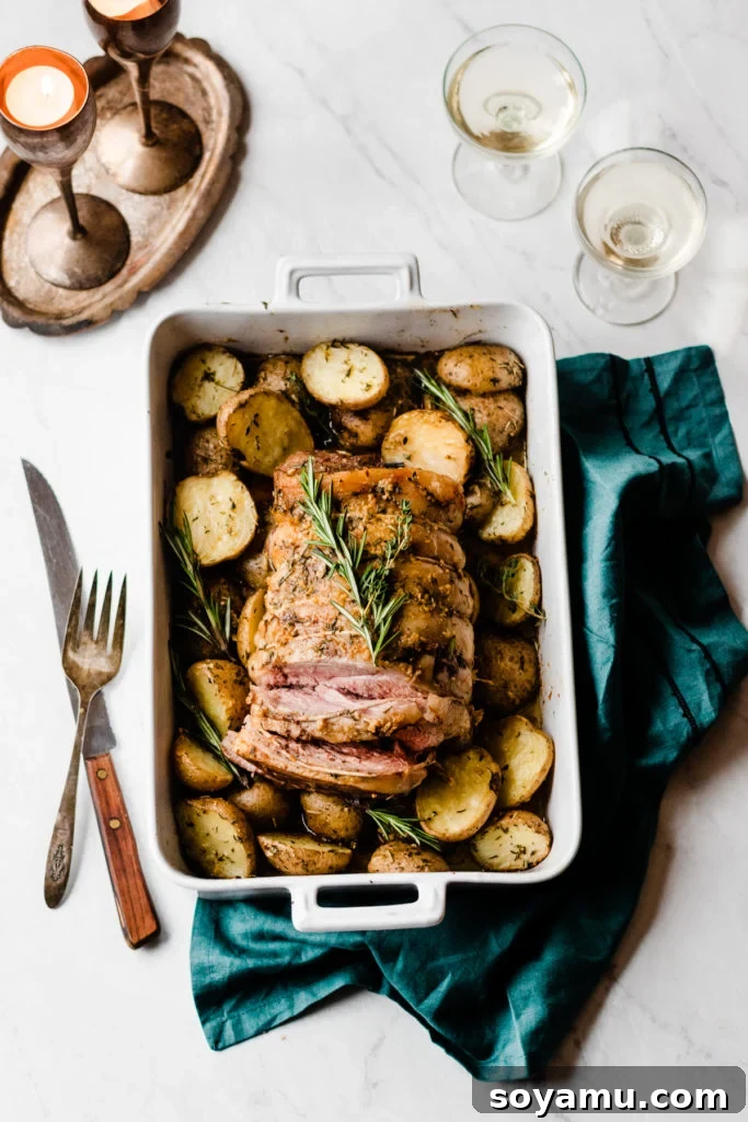 Beautifully sliced lamb and roasted potatoes, ready to serve. Sliced Lamb Roast with Herbed Garlic Butter Potatoes on a platter - Tender, juicy slices of roasted lamb served alongside perfectly golden and aromatic garlic butter potatoes, ready for a holiday meal. Shows the final plating and inviting presentation of the dish. #PlatedDish #HolidayFood #DinnerPresentation #CookedLamb #PotatoSide