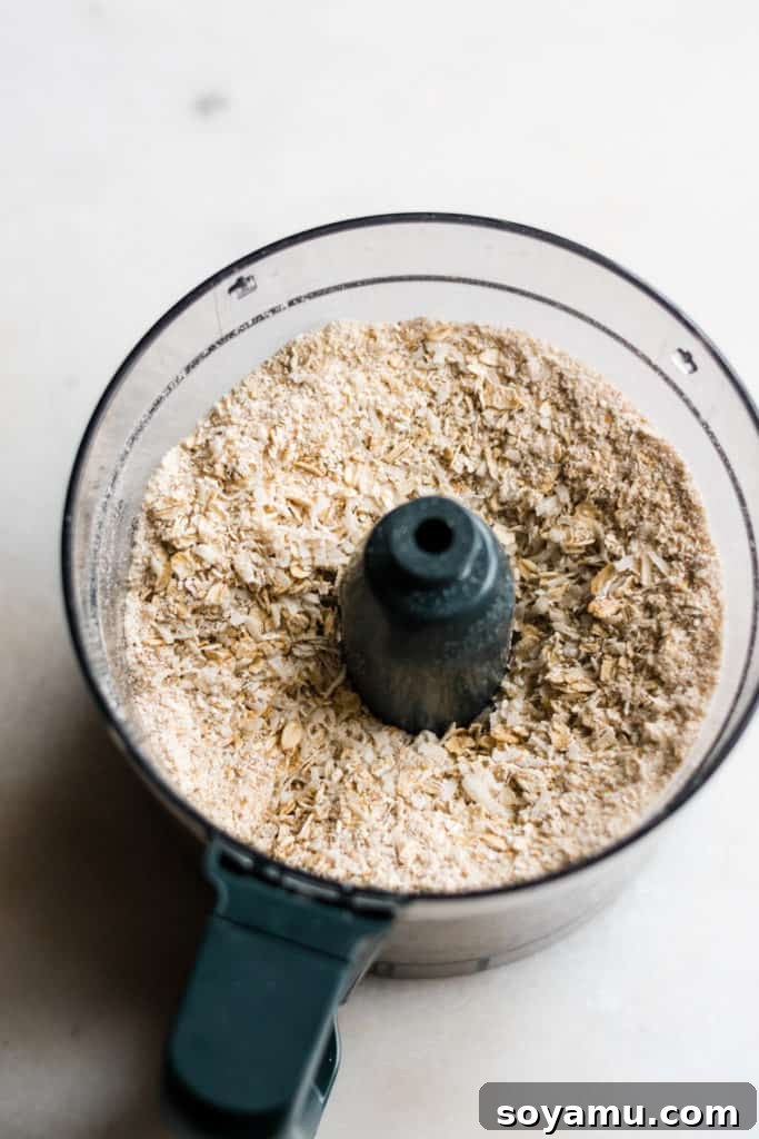Making Oat Flour for Healthy Energy Bites Food processor with oats being pulsed into oat flour.
