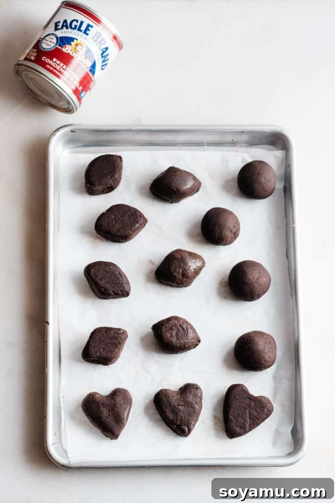 Creative cake pop shapes for themed parties Hand-formed chocolate cake pops in festive shapes, including footballs and hearts, ready for chilling.
