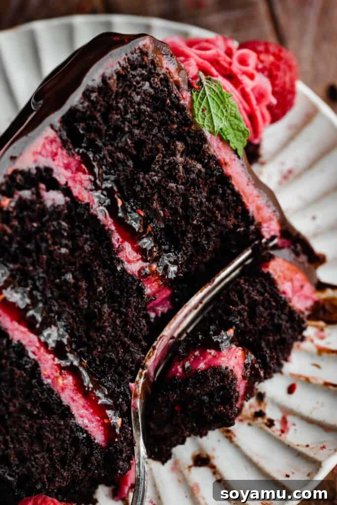 Decadent Raspberry Chocolate Delight 11 A close-up of a slice of cake with a fork poised to take a bite, emphasizing its deliciousness.