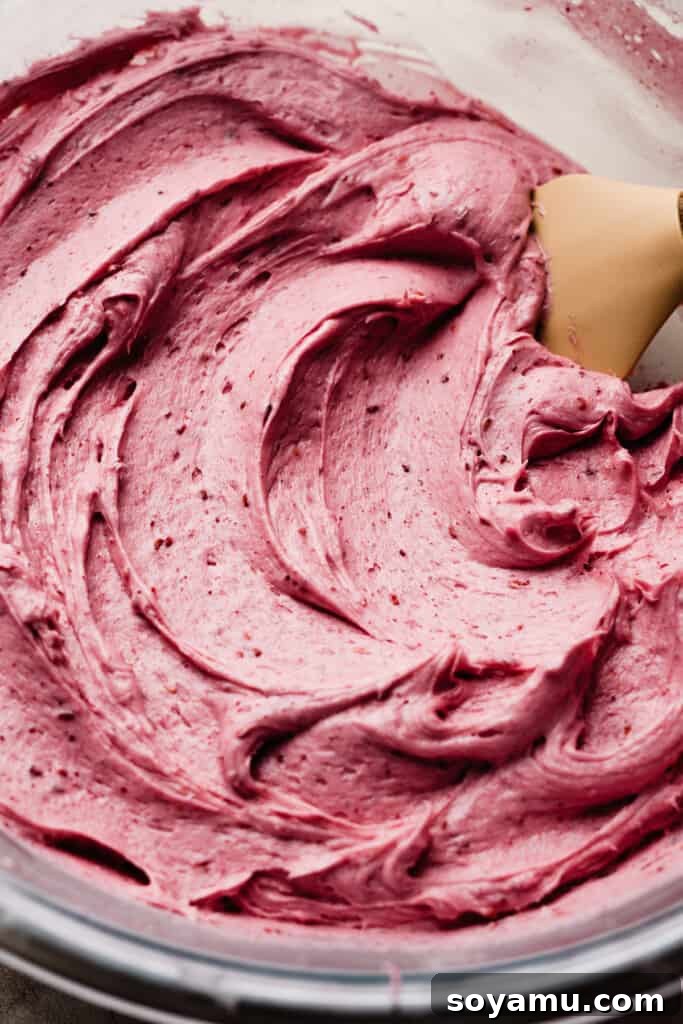 Decadent Raspberry Chocolate Delight 6 A close-up of a bowl filled with fluffy, pink raspberry cream cheese frosting.