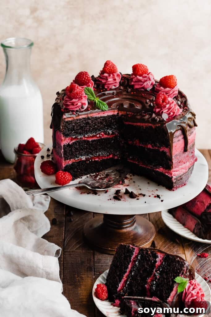 Decadent Raspberry Chocolate Delight 10 The sliced chocolate raspberry cake on a cake stand, topped with elegant frosting swirls and fresh raspberries.