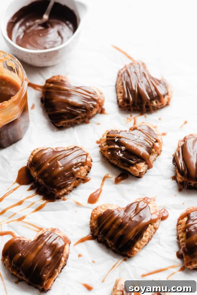 Nutella Pop Tarts with glaze and caramel Freshly baked Nutella Pop Tarts on a cooling rack, with a jar of homemade salted caramel sauce and a bowl of Nutella glaze nearby.