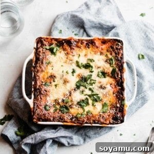 A pan of lasagna topped with melty cheese and fresh parsley.
