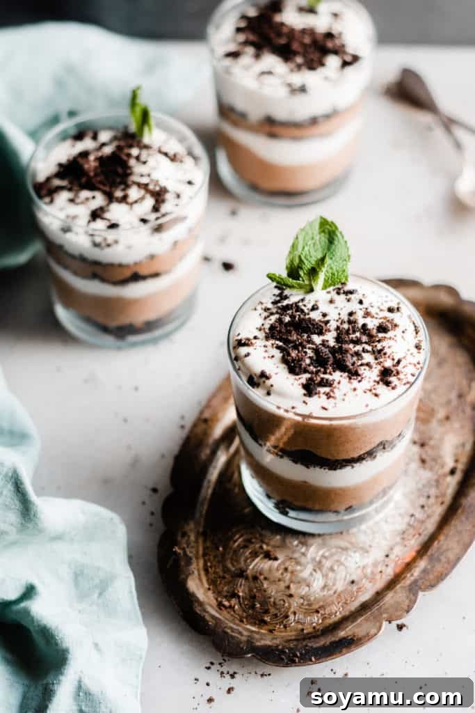 Bailey's Chocolate Mousse Parfaits - Silky smooth layers of Irish cream-infused whipped cream, chocolate whipped cream, and crushed oreos make up these delightful personal-sized desserts! These desserts are so easy to make and are no-bake! Perfect for St. Patrick's Day or any other celebration. Bailey's Chocolate Mousse Parfaits with layers of Irish cream and chocolate whipped cream and crushed Oreos in a glass