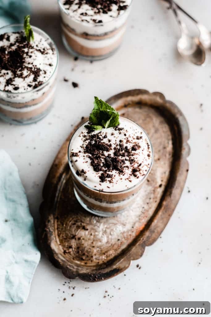 Bailey's Chocolate Mousse Parfaits - Silky smooth layers of Irish cream-infused whipped cream, chocolate whipped cream, and crushed oreos make up these delightful personal-sized desserts! These desserts are so easy to make and are no-bake! Perfect for St. Patrick's Day or any other celebration. Two glasses of Bailey's Chocolate Mousse Parfaits, showcasing the beautiful layers