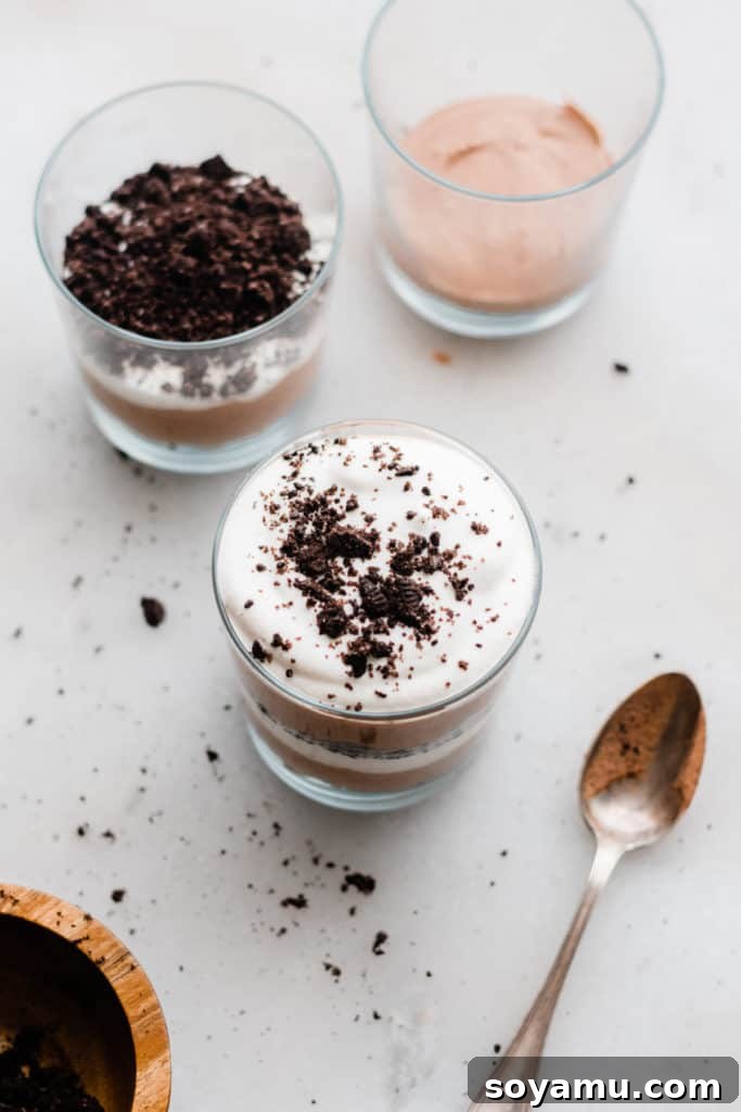 Bailey's Chocolate Mousse Parfaits - Silky smooth layers of Irish cream-infused whipped cream, chocolate whipped cream, and crushed oreos make up these delightful personal-sized desserts! These desserts are so easy to make and are no-bake! Perfect for St. Patrick's Day or any other celebration. Completed layers of Oreo crumbs, chocolate mousse, and Irish cream whipped cream in a parfait glass