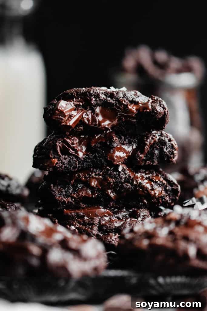 Triple Chocolate Chunk Cookies - World, meet Triple Chocolate Chunk Cookies! Ultra fudgy, with crackly tops - and three kinds of chocolate chunks! We're mixing semi-sweet, milk, and dark chocolate to make the richest possible chocolate cookie. Sprinkle some flaky sea salt over those melted pools of chocolate and dive in to dessert heaven! #chocolatecookies #cookierecipes #dessertrecipes #cookies #chocolaterecipes #chocolatedesserts #bluebowlrecipes | bluebowlrecipes.com A stack of cookie halves, showing the ultra fudgy insides of triple chocolate chunk cookies, perfect for showcasing their rich texture.